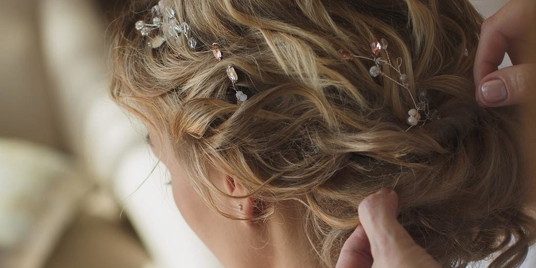 A woman is putting her hair in the back of her head.