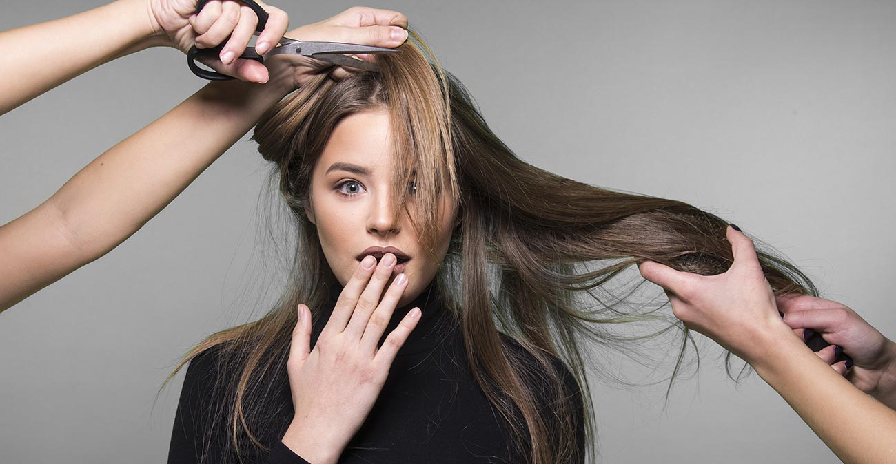 A woman is combing her hair with a pair of scissors.