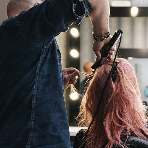 A person with pink hair is getting her hair done