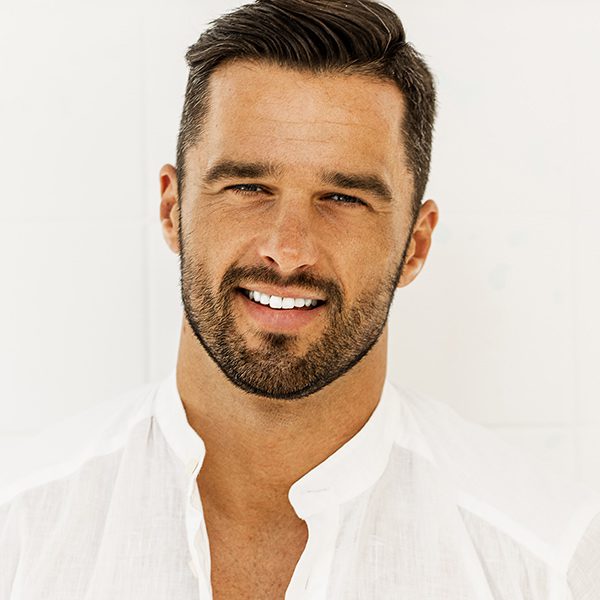 A man with beard and white shirt smiling for the camera.