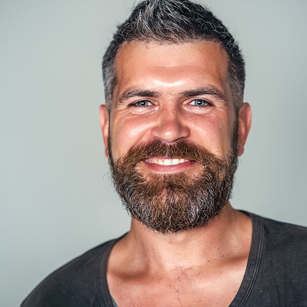 A man with a beard and mustache smiling for the camera.