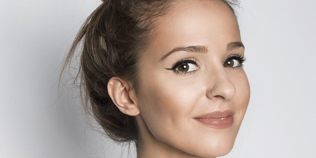 A woman with a bun in front of a white wall.