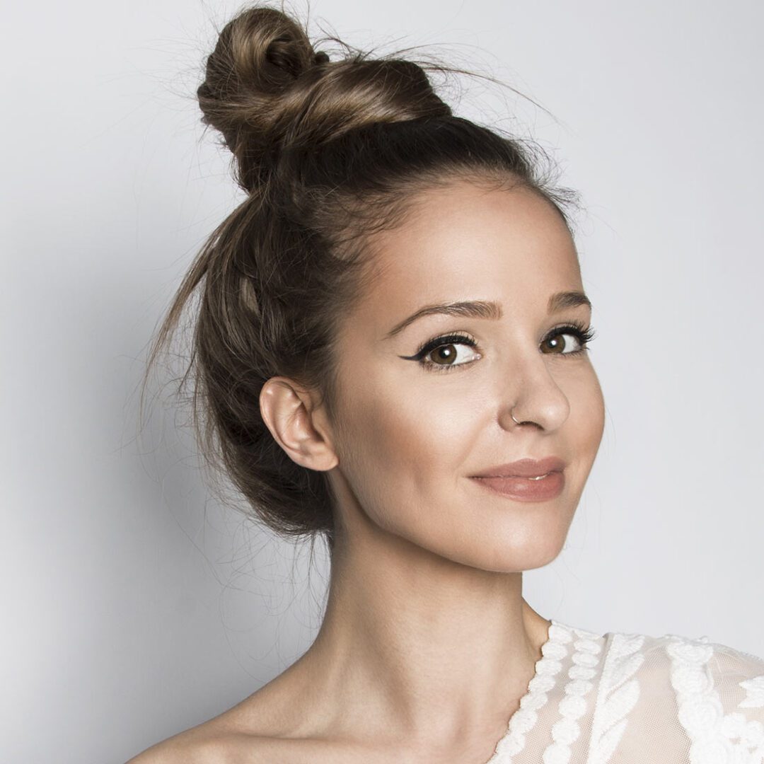 A woman with a bun in front of a white wall.