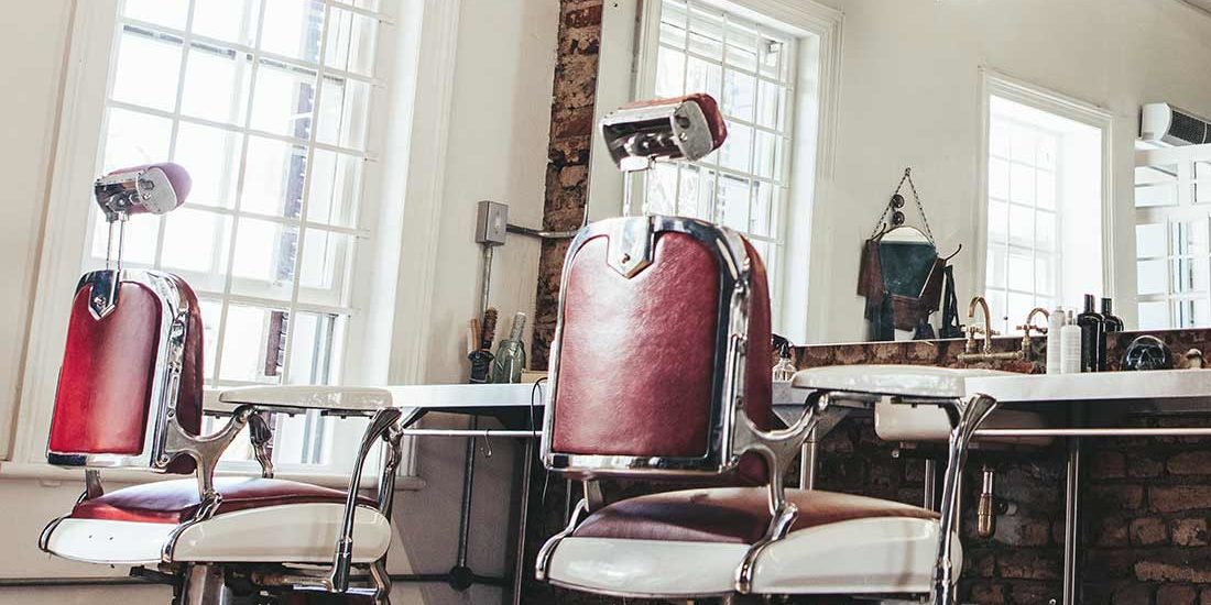Two barber chairs in a room with mirrors