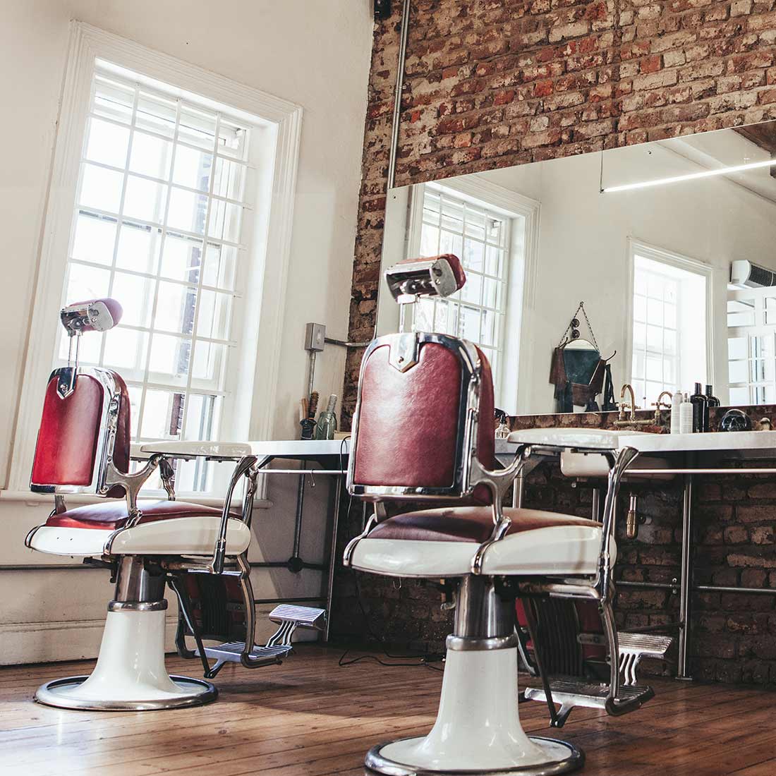 Two barber chairs in a room with mirrors