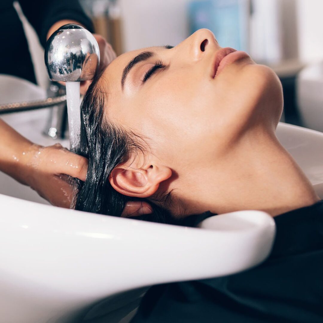 A woman getting her hair washed in the sink.