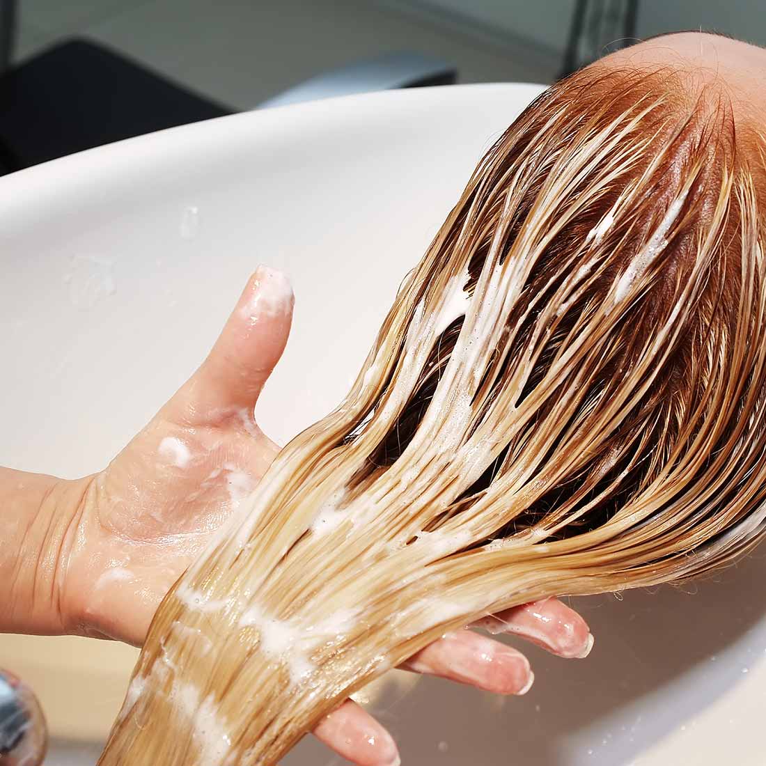 A person washing their hair in the sink.