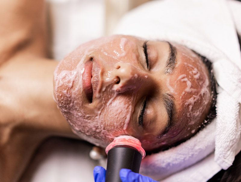 A woman is getting her face washed with a device.