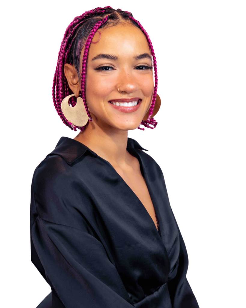 A woman with pink hair and earrings smiles.